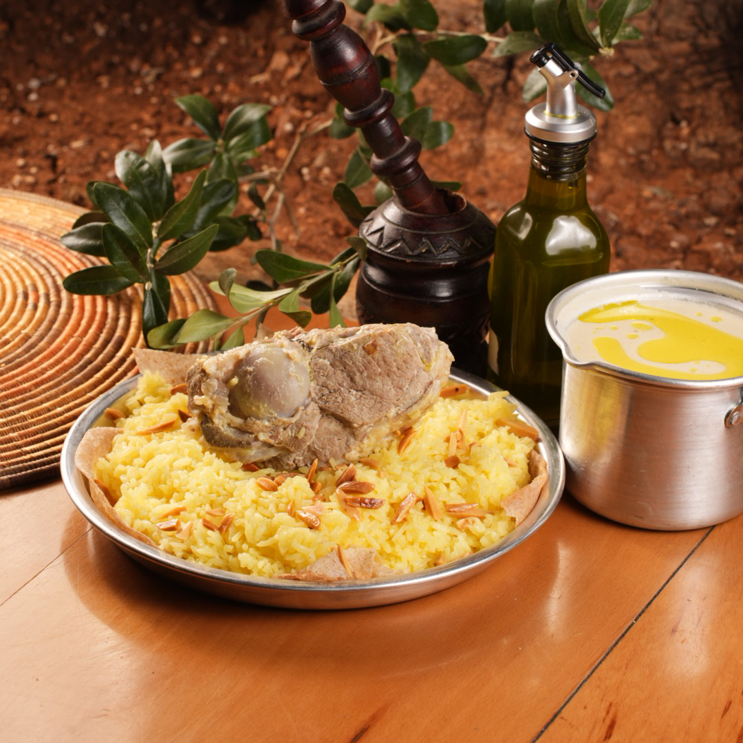 A plate of mansaf — lamb over rice with toasted nuts and jameed sauce