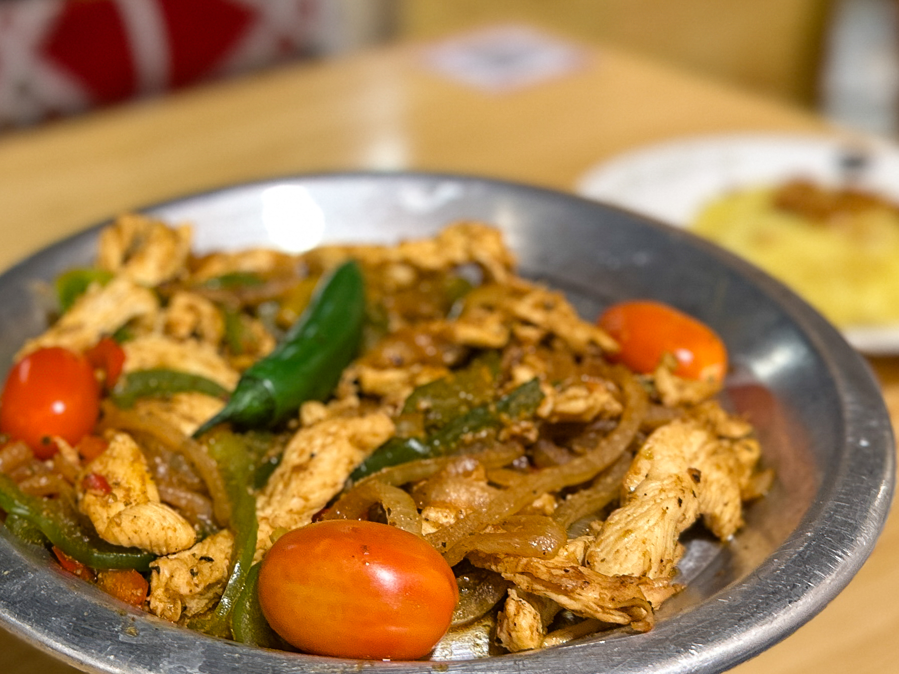 A cast-iron skillet of Khashoka chicken sajia finished with vegetables and spice
