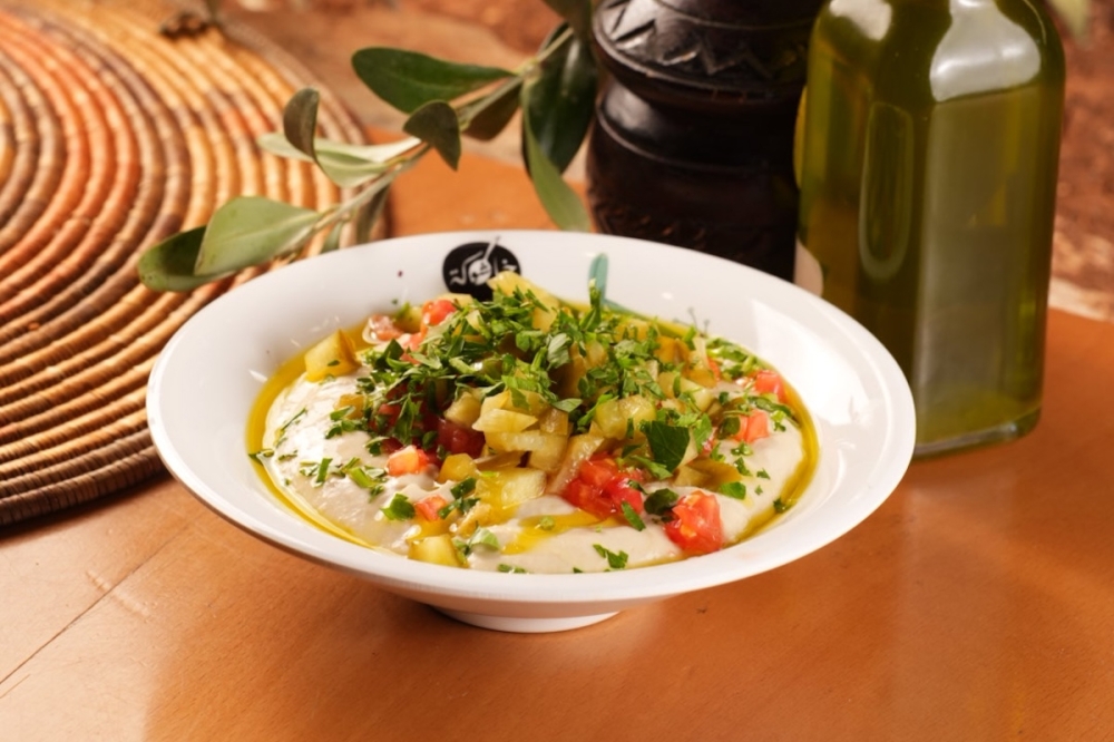 A bowl of Khashoka hummus, finished with olive oil and spice